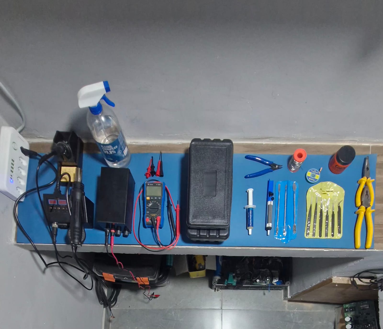 An ultra-clean, modern electronics diagnostics station featuring a powered-on digital oscilloscope displaying a precise waveform, a bench multimeter reading stable values, and a partially disassembled inverter module connected via shielded cables. The devices sit on a matte grey anti-static bench surface with cable routing kept tidy and professional. Neutral, cool-toned studio lighting emphasizes the clarity of display screens and the textured surfaces of plastic enclosures and metal heat sinks, casting controlled, minimal shadows. Shot from a slightly elevated front angle with sharp focus throughout, the image conveys a meticulous, reliable, and expert environment. The background includes softly blurred storage drawers labeled for components, suggesting systematic repair of inverter technology and frequency drives, all rendered in realistic, high-resolution photographic style.